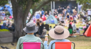 An older couple in lawn chairs at a crowded outdoor concert