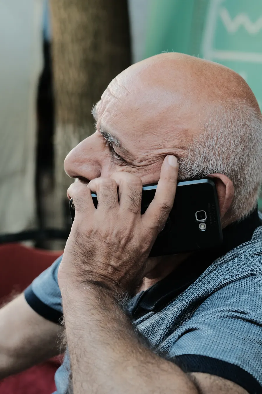 Close-up of an older man pressing a phone to his ear