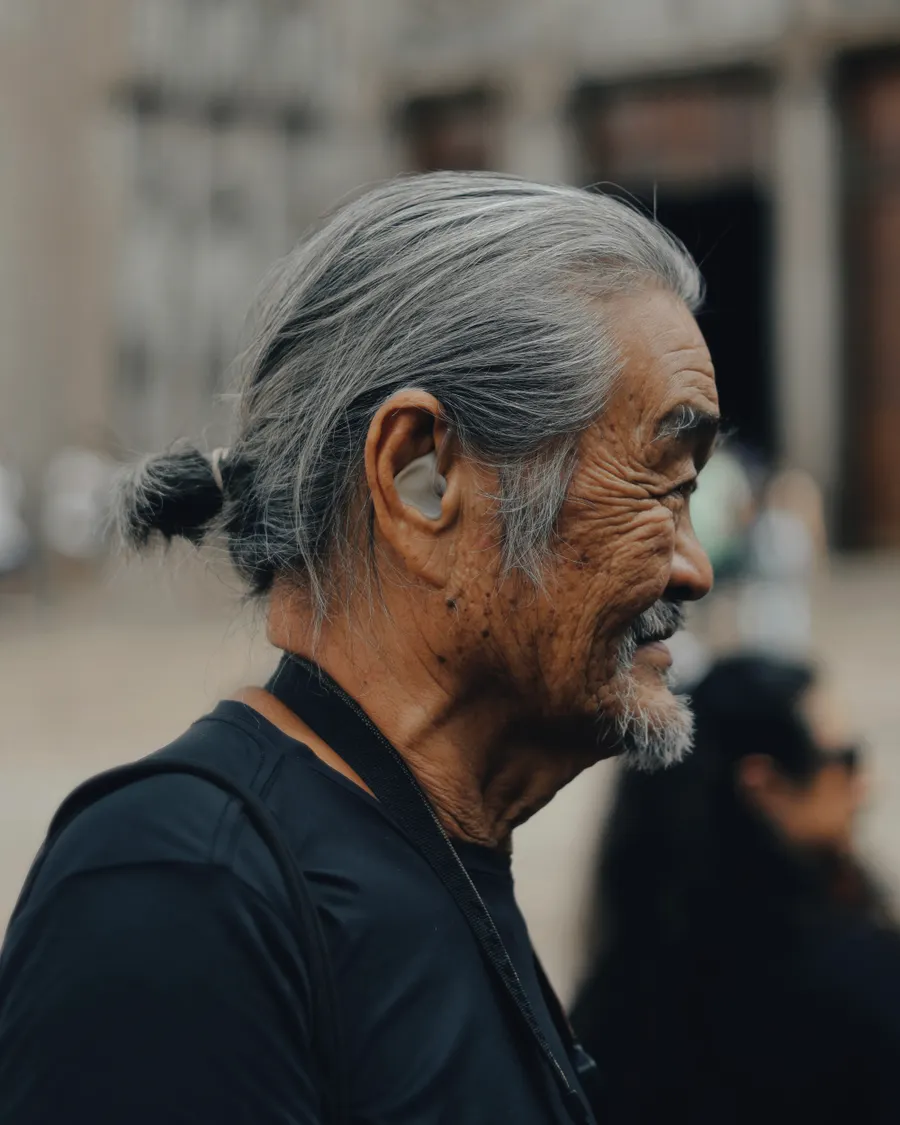 An older man outdoors wearing a small in-ear hearing aid