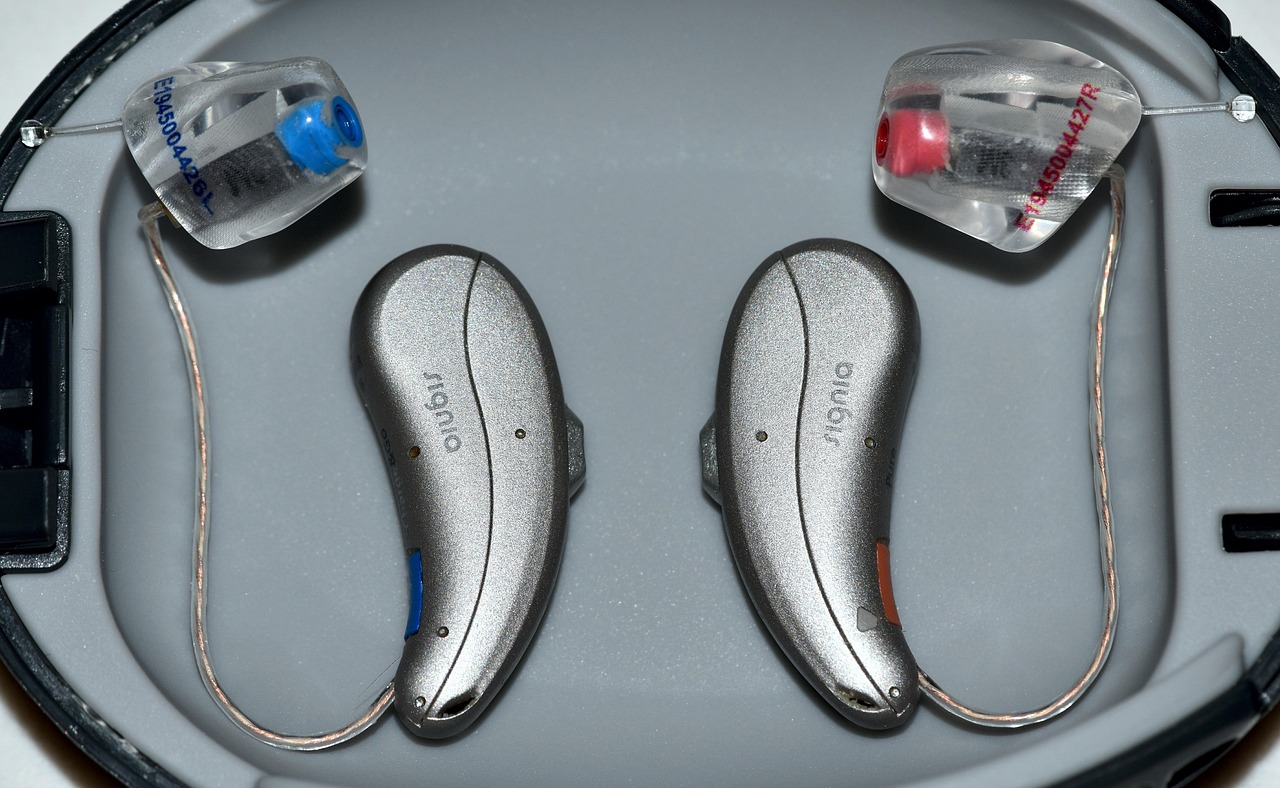 A pair of behind-the-ear hearing aids resting in their case